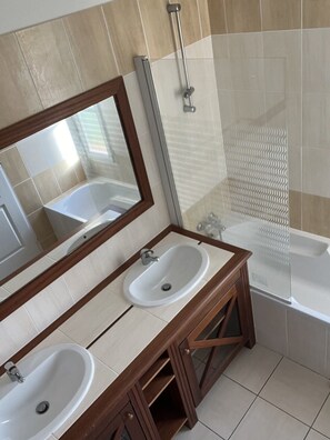 Bathroom features a dual sink vanity, bathtub, and glass shower enclosure.