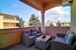 A balcony with wicker furniture, a table, and a column. - Apartment in Medulin Near Beach (Medulin)