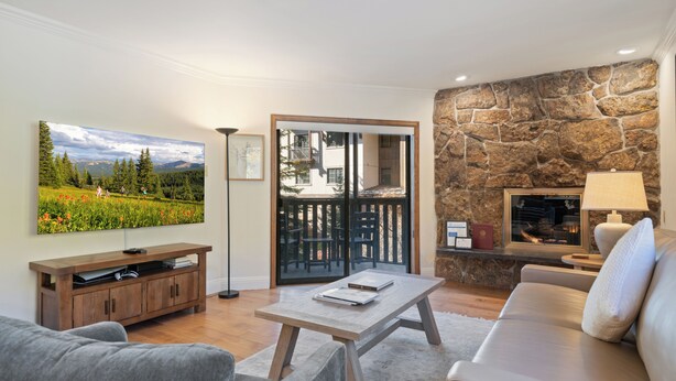 A living room with a stone wall, a sofa, a coffee table, and a TV on a wooden stand.