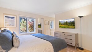 A bedroom with a large bed, a dresser, a mirror, and a painting on the wall.