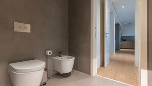 Une salle de bain moderne équipée de toilettes, d’un bidet et d’un porte-papier pour bidet.