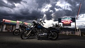 A motel sign with neon lights, two motorcycles parked in front, and a cloudy sky. - Maverick Motel and Glamp Ground (Raton)