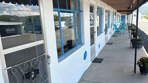 A motel with a covered walkway, multiple windows, and outdoor seating. - Maverick Motel and Glamp Ground (Raton)