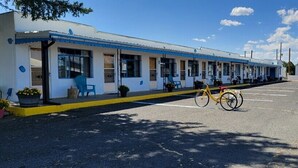 A motel with a row of rooms, a yellow bicycle parked in front, and a clear blue sky. - Maverick Motel and Glamp Ground (Raton)