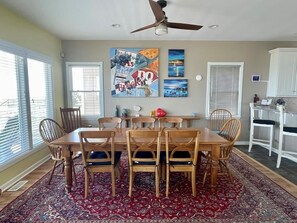A dining area with a wooden table and chairs, a ceiling fan, and artwork on the walls.