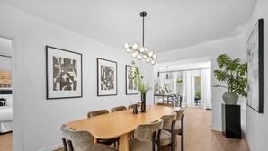 Zona pranzo moderna con tavolo e sedie in legno, opere d'arte alle pareti e un lampadario.