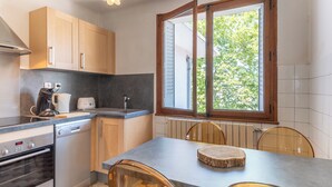 A kitchen with wooden cabinets, a Bosch oven, a coffee maker, and a window with a view of trees.