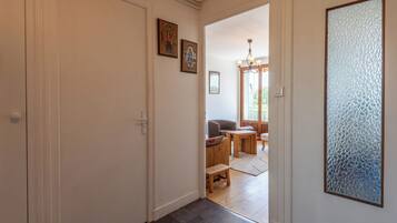 Un couloir doté d’un plancher en bois, d’une porte et d’une vue sur un espace de vie comprenant un canapé et une table.