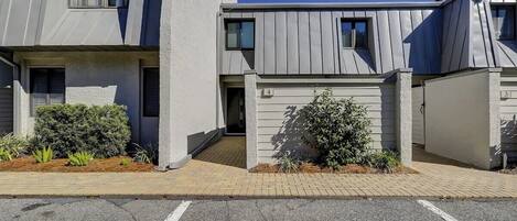 A modern building with a flat roof, a gated entrance, and a paved driveway.