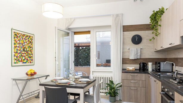 Een moderne keuken met een eethoek, een groot raam en een klok aan de muur.