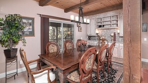 A dining area with a wooden table and chairs, a chandelier, and a stone fireplace. - RH465- Ultimate Mountain Retreat (Zephyr Cove)