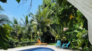 A swimming pool with wooden deck chairs and a concrete pathway. - Casa Yamann (Manzanillo)