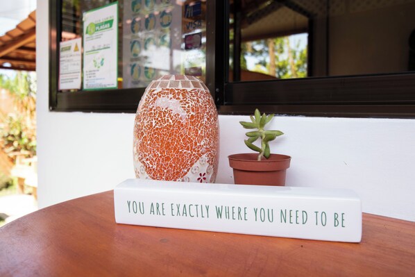 A table with a sign that reads "YOU ARE EXACTLY WHERE YOU NEED TO BE" and a mosaic vase. - Casa Yamann (Manzanillo)