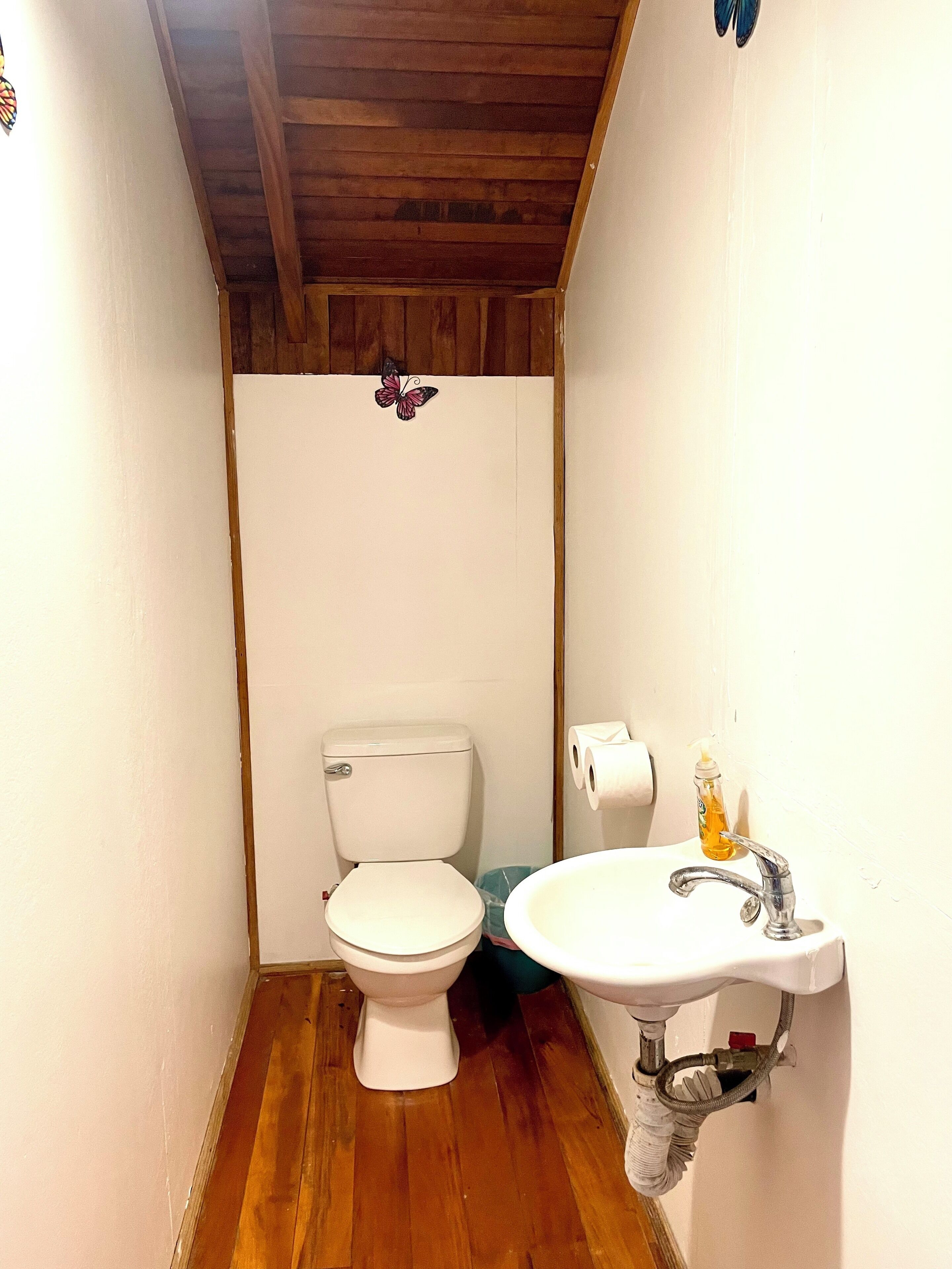 Un baño pequeño con inodoro, lavamanos y piso de madera.