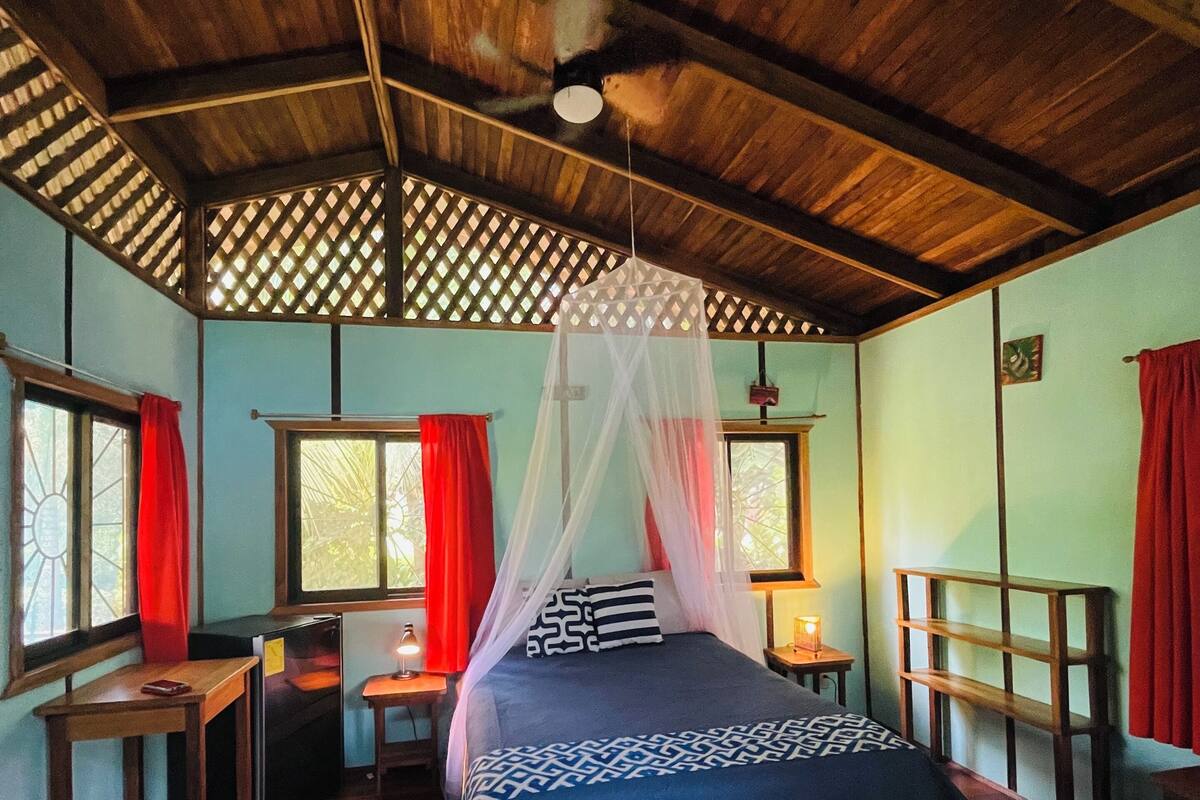 A room with a bed, a desk, a chair, and a nightstand.