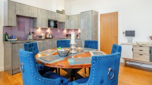 Uma cozinha moderna com armários cinza, uma ilha central e cadeiras estofadas em azul.
