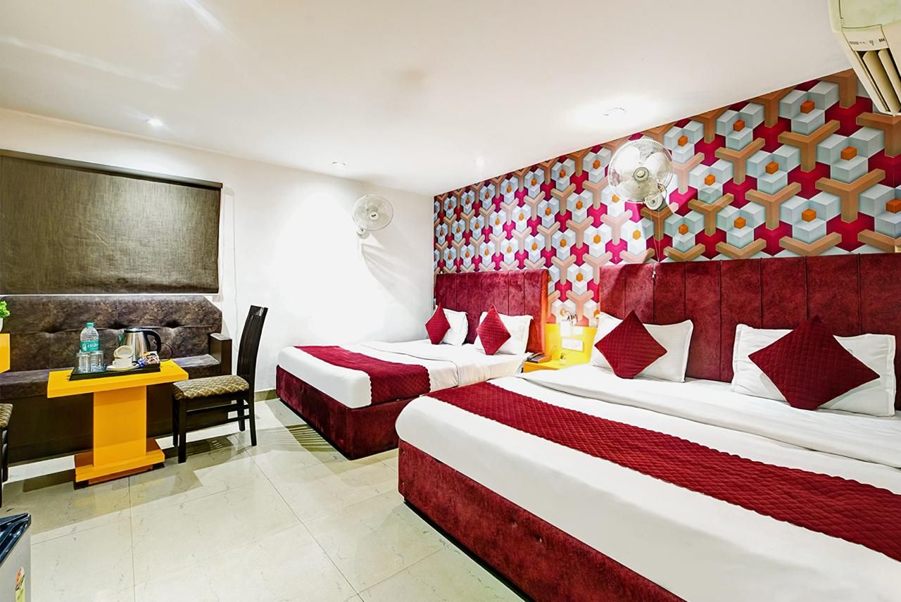 Une chambre d’hôtel avec deux lits, un bureau avec une chaise, une grande fenêtre et un mur décoré d’un motif.
