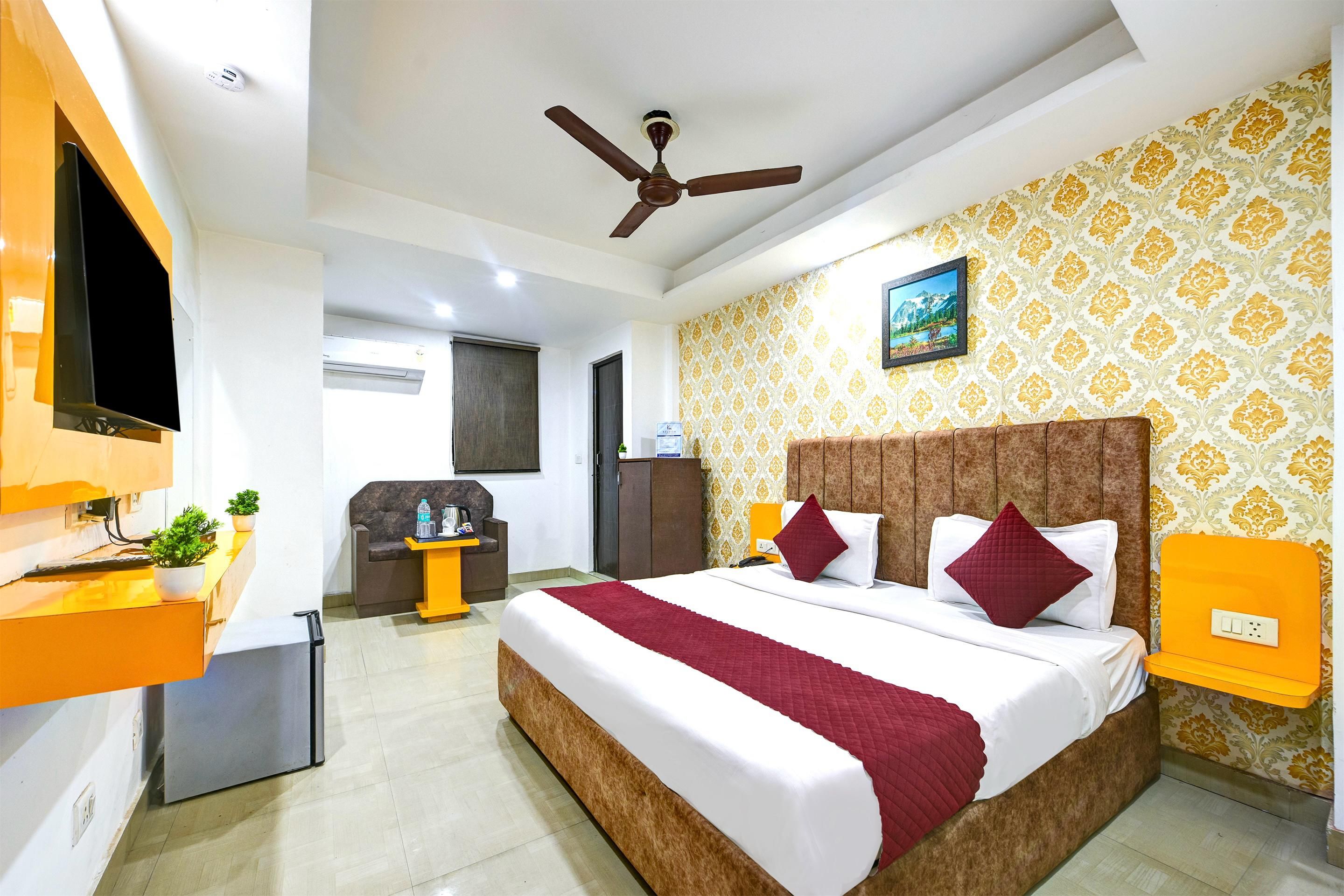 A hotel room with a bed, a desk, a chair, a television, and a ceiling fan.