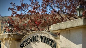Un panneau indiquant l’entrée de Scenic Vista Estates, avec un mur de pierres et une végétation desséchée devant.
