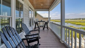 A covered porch with wooden flooring, white railings, and black Adirondack chairs. - Seven Bedroom Channel Front Home with a Private Pool and Hot Tub (Garden City Beach)