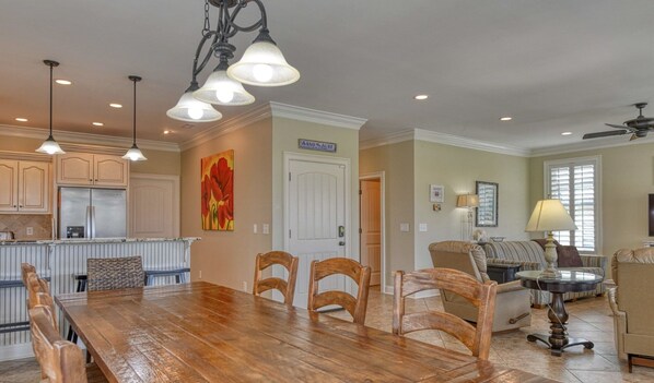 A spacious kitchen with a dining area, wooden chairs, and a large table.