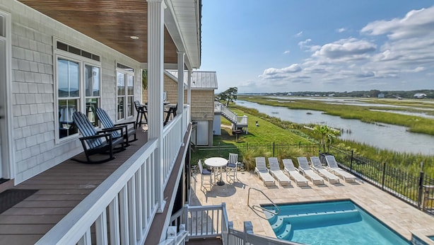A balcony with outdoor seating and a view of a river. - Seven Bedroom Channel Front Home with a Private Pool and Hot Tub (Garden City Beach)