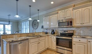 A kitchen with granite countertops, stainless steel appliances, and light-colored cabinetry.