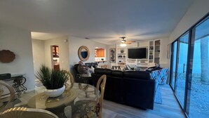 Una sala de estar moderna con una mesa de comedor de vidrio, un sofá y un televisor.