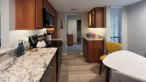 Una cocina moderna con armarios de madera, encimera de mármol y una silla amarilla.
