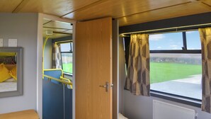 Un compartiment de train équipé d’un lit, d’une petite table, d’un miroir et d’une fenêtre avec des rideaux.