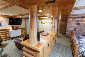 A wooden interior with a bar area, a television, and a stone wall. - Cabin in Lakewood right on Snowmobile Trails! (Lakewood)