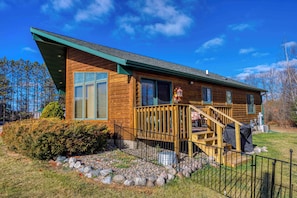 A wooden cabin with a deck, a staircase, and a stone pathway leading to the entrance. - Cabin in Lakewood right on Snowmobile Trails! (Lakewood)