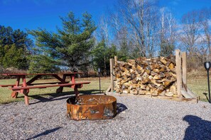 A picnic table, a metal fire pit, and a stack of firewood. - Cabin in Lakewood right on Snowmobile Trails! (Lakewood)