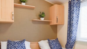Un dormitorio con dos camas, armarios de madera y plantas en macetas.