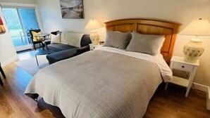 Une chambre avec un grand lit, des tables de chevet, une chaise et une vue sur l’extérieur.