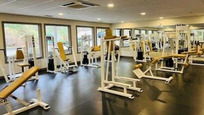 Une salle de sport équipée de divers appareils d’exercice, dotée de grandes fenêtres et présentant un design moderne et épuré.