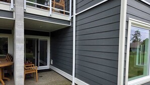Une maison à deux étages dotée d’un balcon, d’une porte-fenêtre coulissante et d’un patio aménagé avec une table et des chaises.