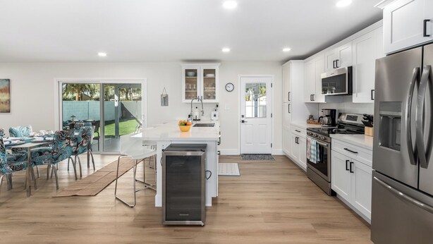 A modern kitchen with white cabinets, stainless steel appliances, and a dining area with patterned chairs. - 3 Bedrooms/2 Bath, Pool & Hot Tub, King Beds, Full Kitchen, Garage, EV Charger (Tempe)