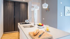 Eine moderne Küche mit einer großen Kochinsel, einer Spüle und einem Herd. Auf der Insel steht eine Fruchtschale und ein Glas Orangensaft.