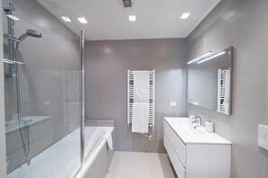 A modern bathroom with a glass-enclosed shower, a bathtub, a white vanity with a mirror, and a towel rack. - BELLAVISTA LAGLIO LAGOON B by Italian Apartments (LAGLIO)