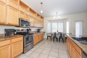 Una cocina con armarios de madera, una estufa de acero inoxidable, un microondas y un comedor con mesa y sillas.