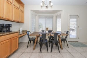Un comedor con una mesa y sillas de madera, una cafetera y un candelabro.