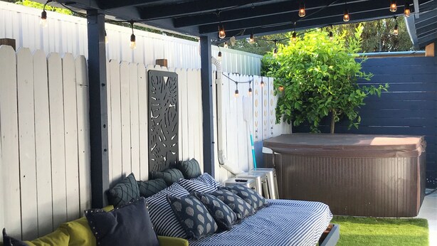 A covered outdoor seating area with a sofa and cushions, a hot tub, and a decorative fence. - 2 Bdrm 2bath Downtown Permit # 4768 (Palm Springs)