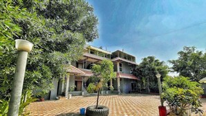 A courtyard with a tiled floor, potted plants, and a building with multiple levels and balconies. - The Moonlight Resort Indore (Sanwer)
