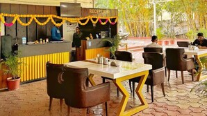 An indoor restaurant with a reception desk, seating area, and ceiling fans. - The Moonlight Resort Indore (Sanwer)
