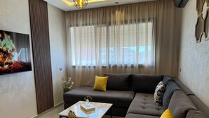 Un salón moderno con un sofá, una mesa de centro y un televisor montado en la pared.