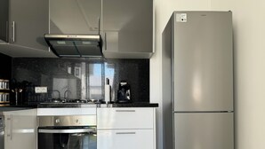 Una cocina moderna con electrodomésticos de acero inoxidable, incluyendo un refrigerador, horno y cafetera.
