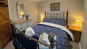 Een slaapkamer met een bed, een dressoir, een spiegel, een nachtkastje en een lamp.