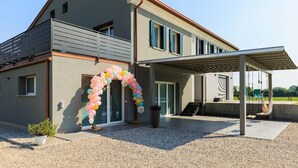 Una casa moderna de dos pisos con un patio cubierto, un balcón y un arco decorativo de globos.