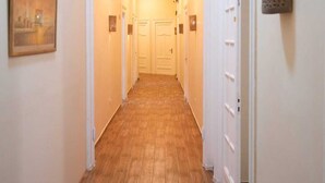 A hallway with wooden flooring, white walls, and doors leading to individual rooms. - Charming Oasis in the Heart of Cairo – Authentic Hospitality Awaits! (Cairo Governorate)